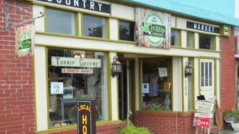 The storefront of a brick building with a sign that reads 'Turnip Greens' and another sign that says 'Country